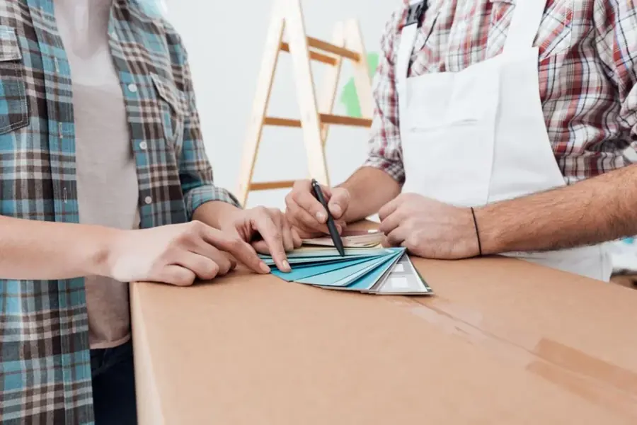 Two people sitting together comparing paint colour sample cards