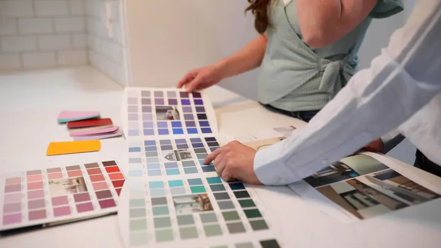 A homeowner browsing paint colour swatches laid out on a table